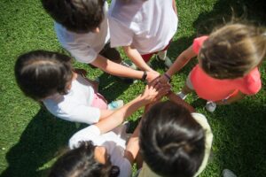 Bambini in cerchio su un prato che uniscono le mani 